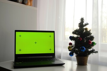 Merry Christmas and Happy Holidays. Green laptop screen on the table