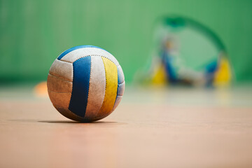 Volleyball on wooden court. Sports ball lying on indoor stadium parquet