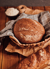 a loaf of bread in a basket with a towel on a wooden background