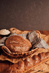 a loaf of bread in a basket with a towel on a wooden background