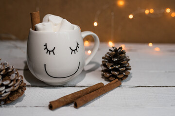 Christmas cocoa with marshmallows and cinnamon in a white coffee cup. coffee cup with a smile with homemade hot chocolate. Photo of a winter drink on a light background