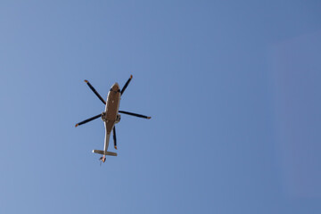Helicopter flying in the blue sky bottom view.