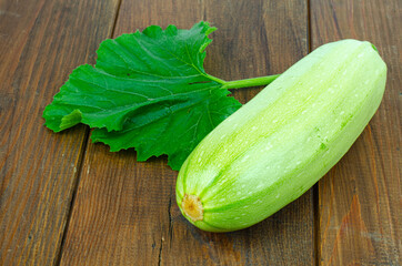 Fresh white zucchini zucchini with green leaf lies on wooden surface. Studio Photo