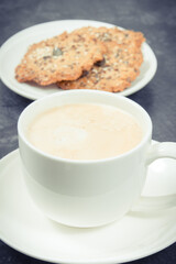 Cup of coffee with milk and fresh baked healthy oatmeal cookies. Delicious crunchy dessert