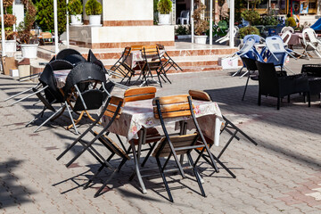Closed cafe terrace due to coronavirus pandemic with old menu table and packed chairs with tables