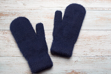 Blue woolen mittens on a wooden background. Winter clothes. Flat lay, top view.