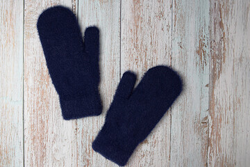 Blue woolen mittens on a wooden background. Winter clothes. Flat lay, top view.
