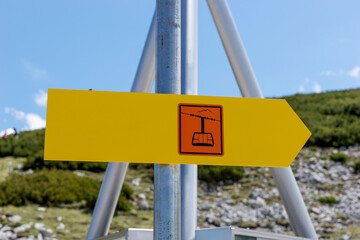 Yellow signboard to the chair lift in the mountains