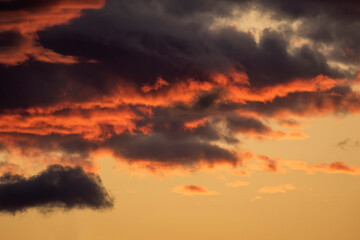 Dramatic stormy cloudscape lit by the setting Sun during sunset in Estonian nature