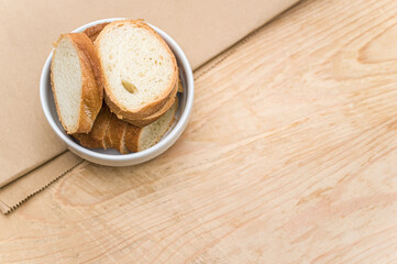 white stoneware bowl with fresh organic sliced bread on a rustic wooden and paper background