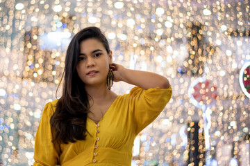 Beautiful brown haired Colombian woman in yellow dress at a mall during the holiday season