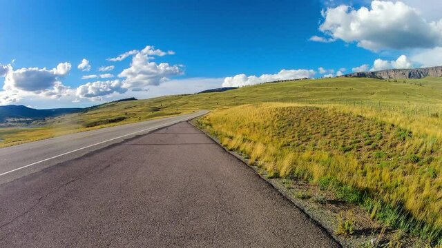 Time Lapse Lockdown Scenic Shot Of Vehicles Moving On Road By Green Landscape Against Cloudy Sky - Creede, Colorado