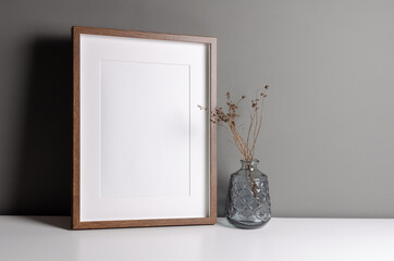 Portrait wooden frame mockup for artwork, photo and print presentation. Grey walll interior with...