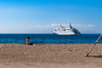 Woman on beach with cruise ship on the horizon