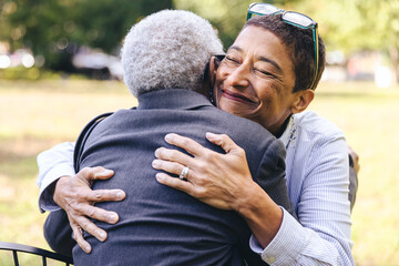 Smiling mixed race woman hugs her elderly mother with her eyes closed