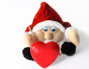 A cute gnome on a white background sits and wants to take a decorative red heart.