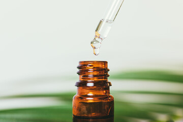 Organic essential oil drop drips into amber glass bottle