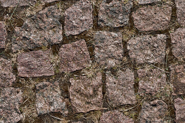 A fragment of a stone-paved road. The background texture of the stone road surface. Pattern.