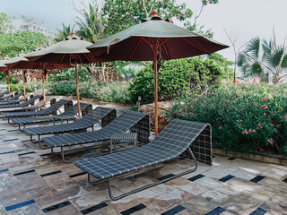 Row of Empty Poolside Benches and Umbrellas at Resort