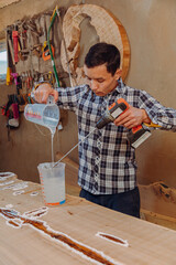 Carpenter mixing epoxy resin with an electric mixer in liquid cup in workshop