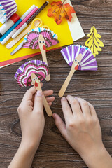 In the hands of a child craft Thanksgiving toy stics puppets turkey. Childrens art project,...