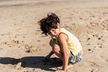 little caucasian girl playing on the beach