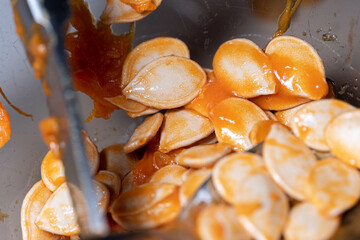 Pumpkin seeds in orange flesh. Cleansing the pumpkin from fresh seeds. Preparing vegetables for halloween.