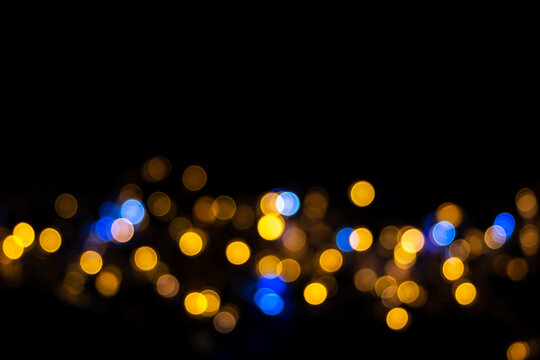 Horizontal stripe of blue and yellow shiny bokeh. Beautiful background of defocused blue and yellow circles © Alena
