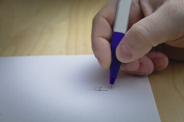 man's hand signing a contract over a desk