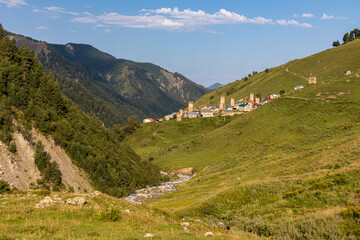 Fototapeta na wymiar Panoramic view on Adishi, a mountain village, located in the High Caucasus, Svaneti Region in Georgia. Svan watch towers can be seen. A hiking trail and a river leads to the village. Solitude