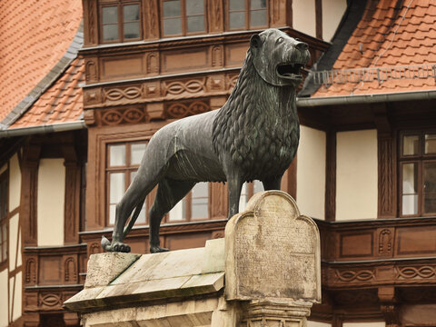 Braunschweiger Löwe, Brunswick Lion statue located in the old town of Braunschweig, Lower Saxony, Germany. Landmark, a symbol of the city. Sculpture isolated in front of historic half-timbered houses.