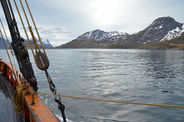 On the way to Trollfjord in the Lofoten Islands in northern Norway. View from the deck of an old sailing ship. A dark and rainy day.