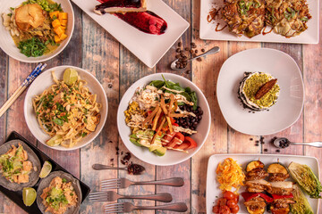 Top view image of vegan food dishes, boletus croquettes, poke bowl with wakame seaweed salad, edamame and pumpkin cubes, artichoke flowers, tacos with heura, vegetable skewers