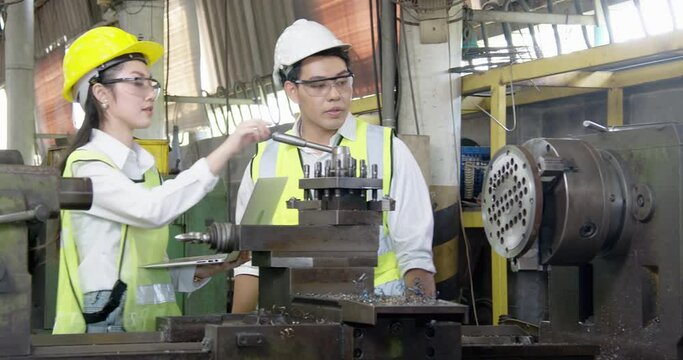 Young professional engineers and trainee wearing safety gear vest helmet reflective learning operate repair machinery plant in industrial factory using tablet to online check specification 

