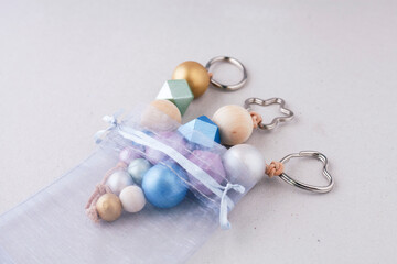 Painted wooden beads key chains in organza gift bag on light background. Wooden beads and hexagon...