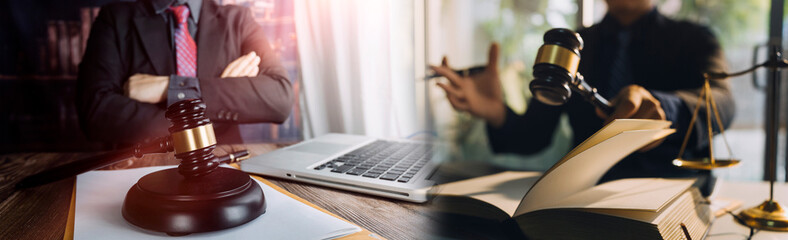 Justice and law concept.Male judge in a courtroom with the gavel, working with, computer and docking keyboard, eyeglasses, on table in morning light