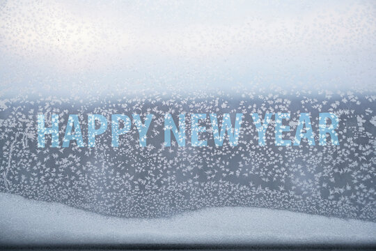 Winter iced pattern on frozen window glass, bad ventilation concept, cold temperature outside and inside. energy or power crisis. 2022 happy new year inscription.