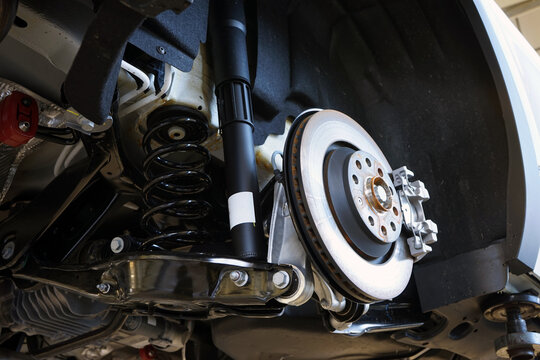A modern car in a car service on a lift with a removed wheel. Elements of the brake system and suspension. Selected focus.