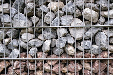 Gray and brown stones in the gabion. Fencing decorative. Retaining wall.