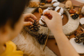 The boy makes a wreath from natural materials. Autumn needlework with handmade children