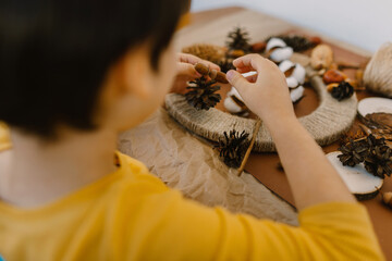 The boy makes a wreath from natural materials. Autumn needlework with handmade children