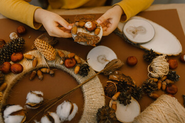 The boy makes a wreath from natural materials. Autumn needlework with handmade children