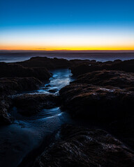 Beautiful twilight on the shores of pichilemu beach with waves crashing against the rocks on the shore.