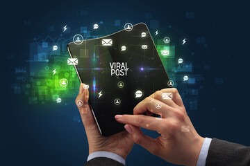 Businessman holding a foldable smartphone, social media concept