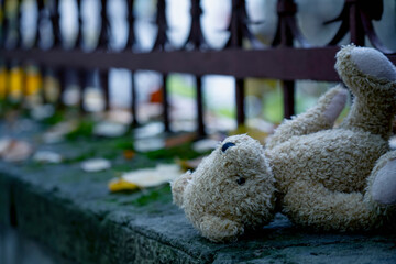 Conceptual image: Lost childhood and loneliness. Dirty teddy bear lying down outdoors. Selective focus.