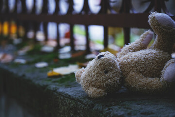 Lost childhood and loneliness. Dirty teddy bear lying down outdoors. Selective focus.