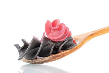 Uncooked colored fusilli pasta with wooden spoon, close-up, isolated on white.