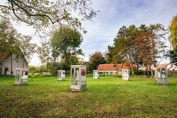 Collection of telephone booths on the lawn of a park in the town of Damme in Flanders, Belgium