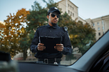 Male police officer in sunglasses holds notebook