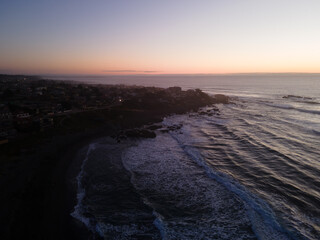 Aerial view of pichilemu being darkened with the sunset in the background.